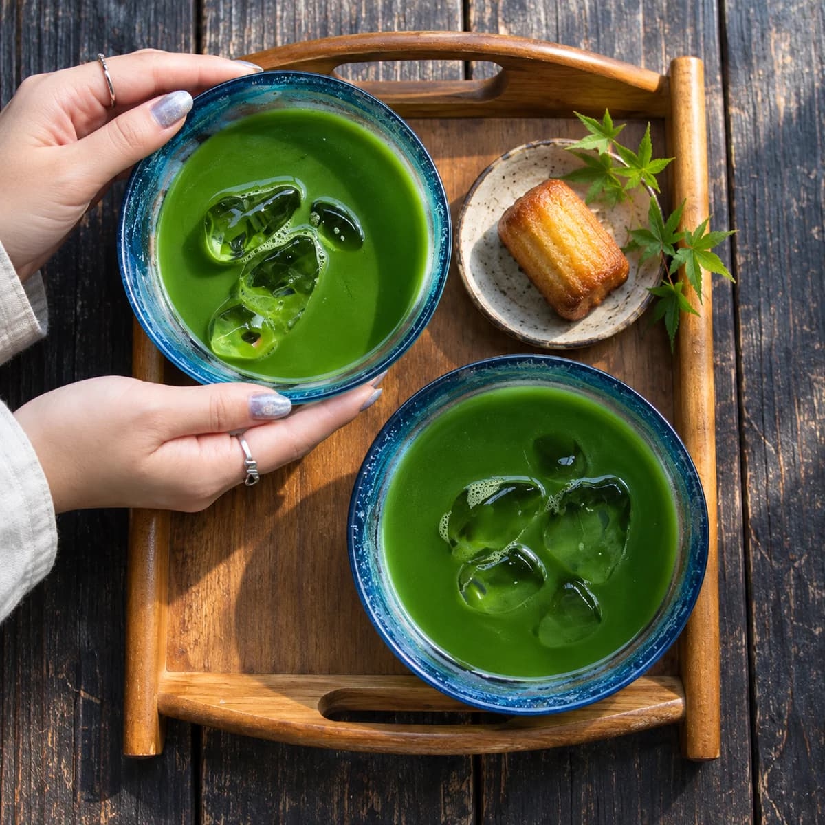 Two blue ceramic bowls of iced matcha on a wooden tray